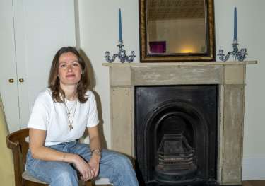 Portrait of woman posing in living room on wooden chair.