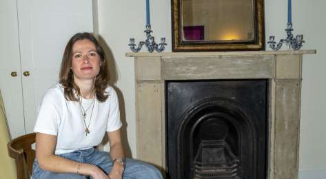 Portrait of woman posing in living room on wooden chair.