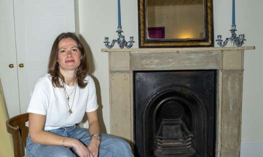 Portrait of woman posing in living room on wooden chair.
