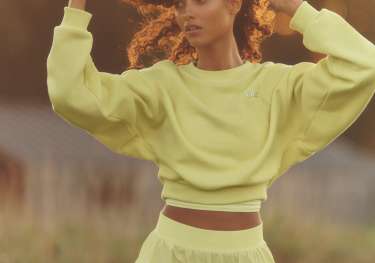 Model wearing yellow sports top and matching shorts.