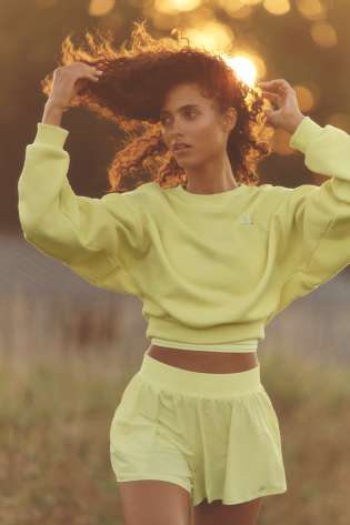 Model wearing yellow sports top and matching shorts.