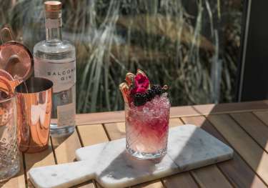 Blackberry cocktail on marble serving board.