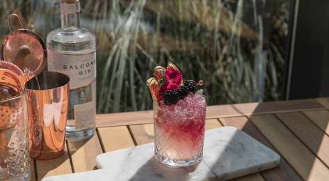 Blackberry cocktail on marble serving board.