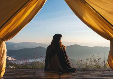 Woman looking at mountain views from a tent.