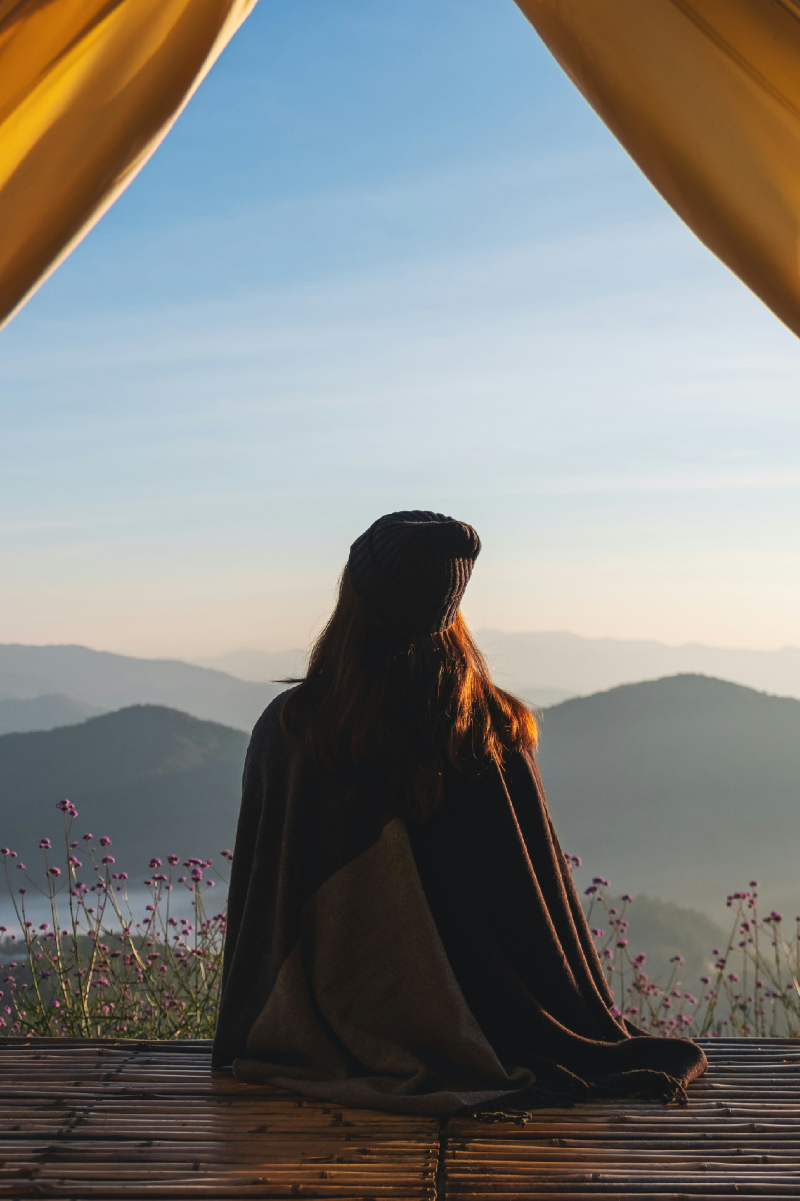 woman looking at mountain views from a tent