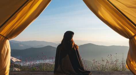 Woman looking at mountain views from a tent.