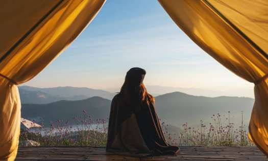 Woman looking at mountain views from a tent.
