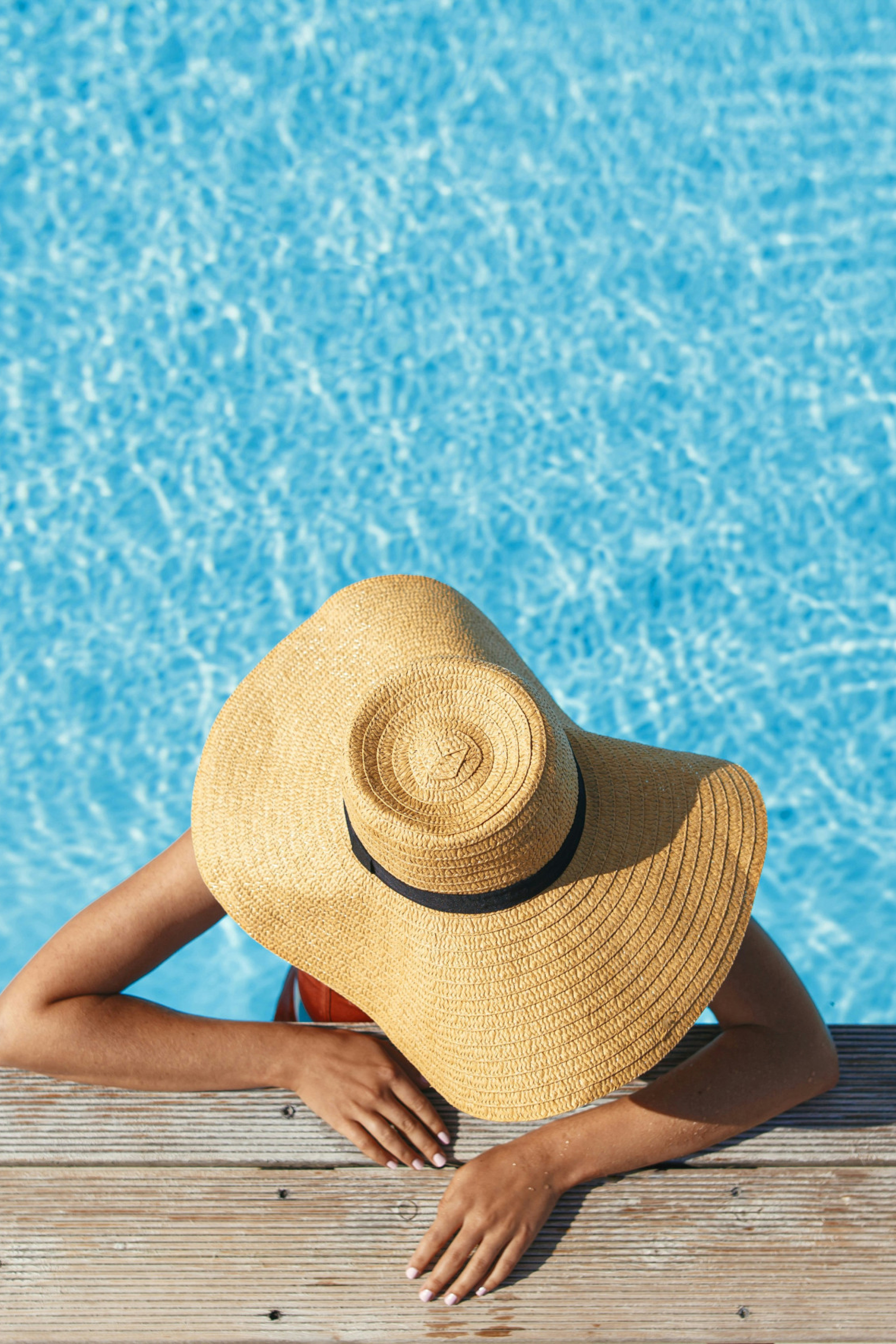 woman relaxing in pool with wide-brim hat