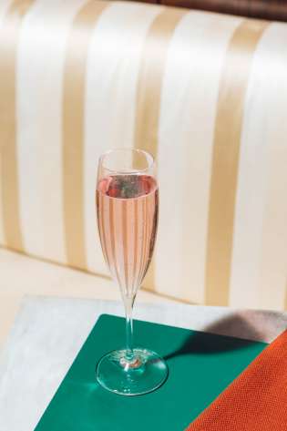 Glass of pink fizz on table.