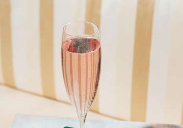 Glass of pink fizz on table.