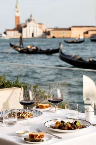 Table set for two beside venice waterway.