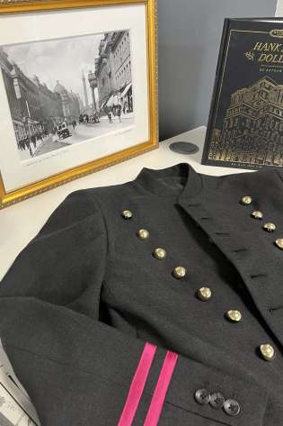 Bell boy jacket on desk with black-and-white photo and gold embossed book.