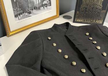 Bell boy jacket on desk with black-and-white photo and gold embossed book.