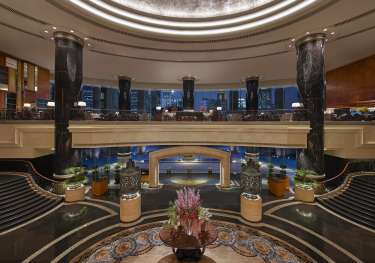 Hotel atrium with vase of flowers in the centre.