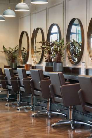 Brown leather chairs and round mirrors inside hair salon.