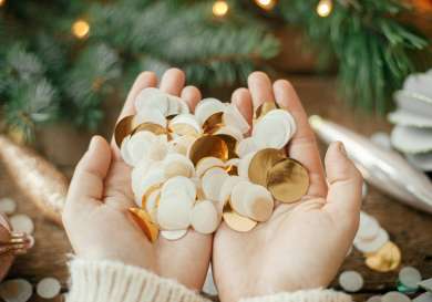 Hands holding white and gold confetti .