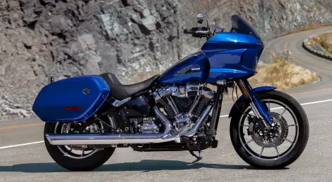 Harley davidson blue bike parked on road .