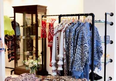Clothes shop with items of clothing folded on glass counters and hanging on racks.