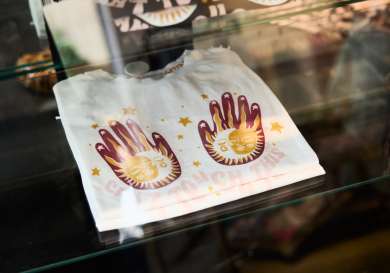Folded T-shirts displayed on glass shelving in shop.