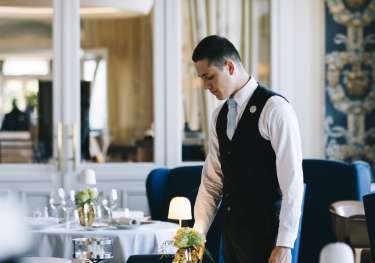 Waiter setting table in hotel restaurant .