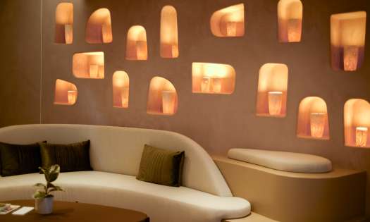 Room inside beauty clinic with curved cream sofa and wall pierced with lights.