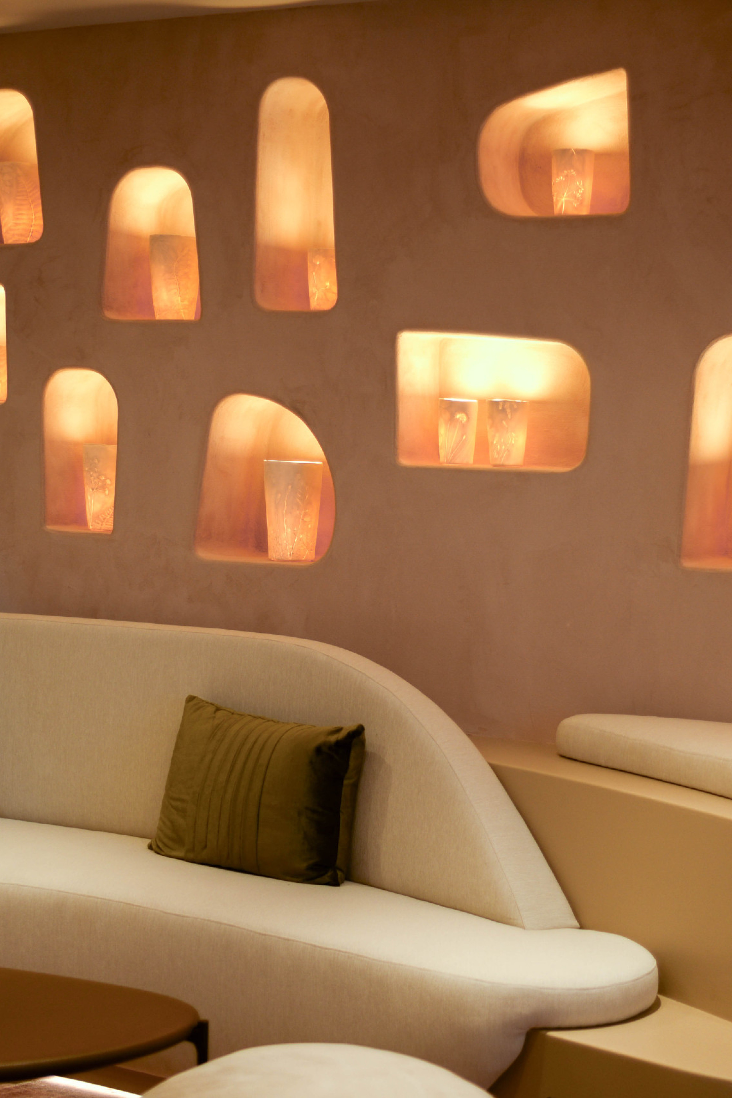 room inside beauty clinic with curved cream sofa and wall pierced with lights