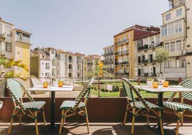 Hotel terrace area in porto with tables and chairs .