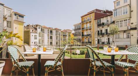 Hotel terrace area in porto with tables and chairs .