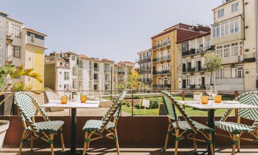 Hotel terrace area in porto with tables and chairs .