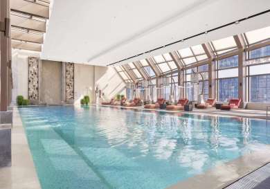 Indoor pool with orange sunloungers .