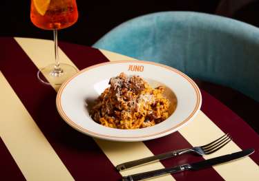 Bowl of pasta on striped table at JUNO London.