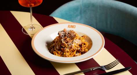 Bowl of pasta on striped table at JUNO London.
