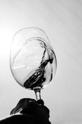 Black-and-white photo of someone swirling glass of wine.