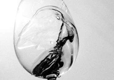 Black-and-white photo of someone swirling glass of wine.