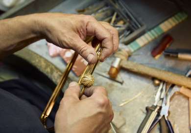 Person making hardware details for handbag.