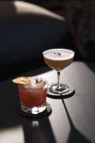 Two cocktails on dark table.