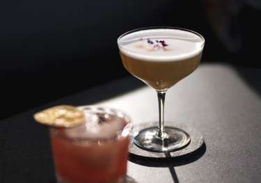 Two cocktails on dark table.