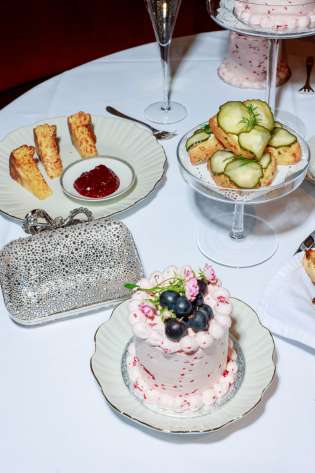 Afternoon tea spread with cakes and sparkly clutch .
