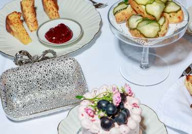 Afternoon tea spread with cakes and sparkly clutch .