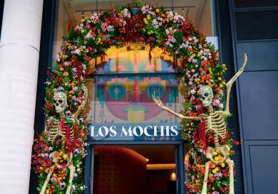 Exterior of los mochis restaurant with floral arch and plastic skeletons .