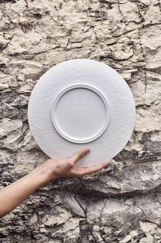 Porcelain plate held up against rock wall .