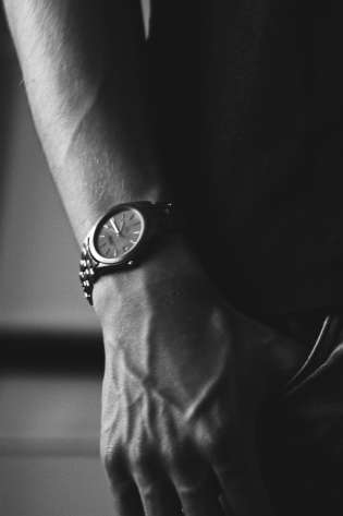 Black-and-white photo of person wearing luxury watch.