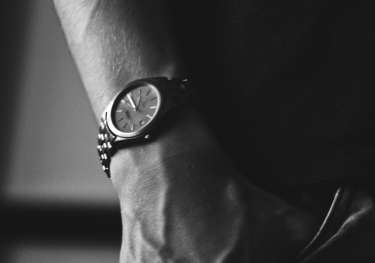 Black-and-white photo of person wearing luxury watch.