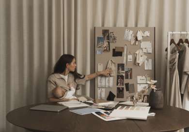 Fashion designer with baby and looking at mood board.