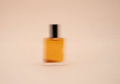 Slow-mo photo of orange perfume bottle.