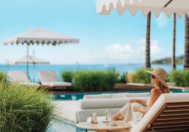 Woman sitting on sun lounger by the pool .