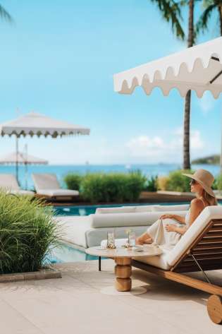 Woman sitting on sun lounger by the pool .