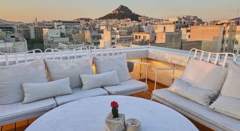 Hotel rooftop area with round table and chairs.