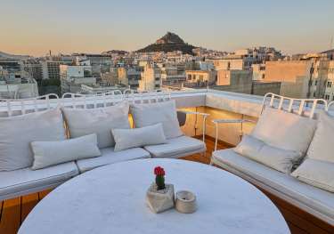 Hotel rooftop area with round table and chairs.