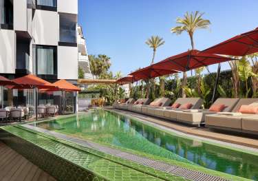 Hotel pool with sunbeds around the edge.